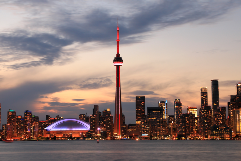 A big city at sunset with a telecommunications tower in the middle